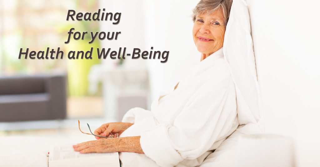 An elderly Caucasian woman in bed with a book and glasses with text "Reading for your Health and Well-Being"